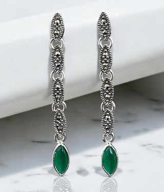 Ziva Silver Marcasite Cocktail Earrings with green gemstone drops, displayed against a white marble background.